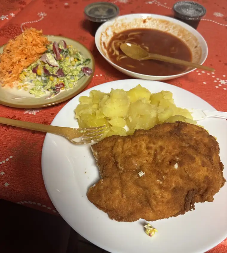 Kotlet schabowy z ziemniakami i surówkami na czerwonym obrusie